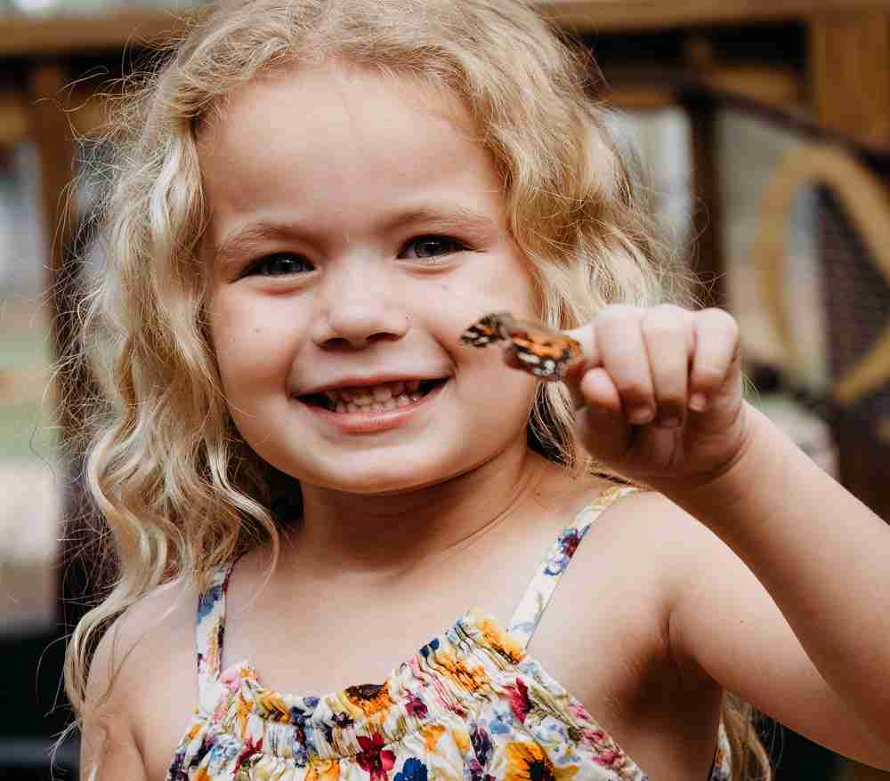 girl with butterfly on finger in butterfly garden at boggy creek airboat adventures